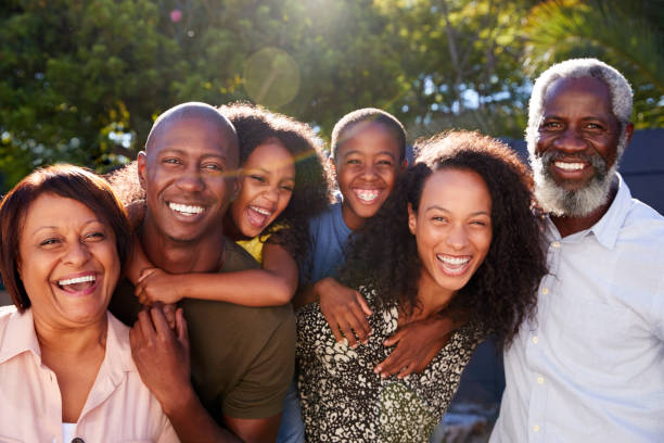 Outdoor Portrait Of Multi-Generation Family In Garden At Home Against Flaring Sun